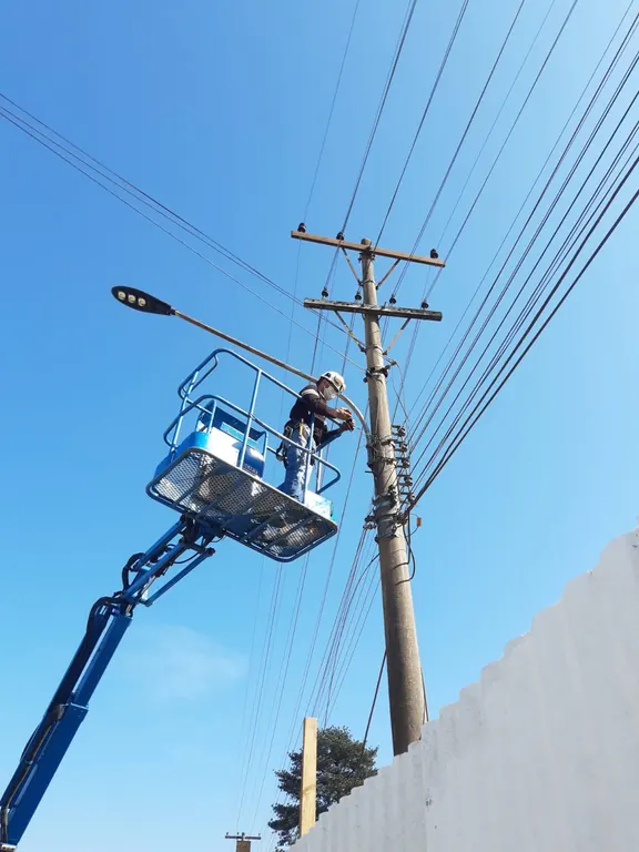 Técnico em cesto aéreo trabalhando na rede elétrica junto ao poste