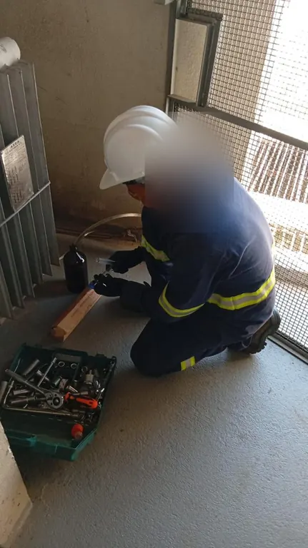 Eletricista ajoelhado com caixa de ferramentas durante manutenção