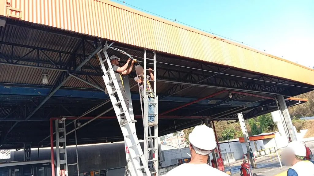 Equipe em escadas instalando linha de vida em cobertura de garagem