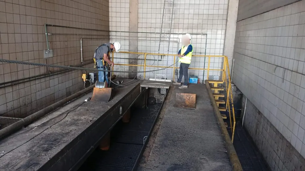 Técnicos instalando linha de vida em área de manutenção com fosso