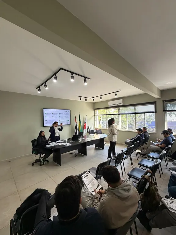 Treinamento em sala com projeção na tela e alunos com o material em mãos