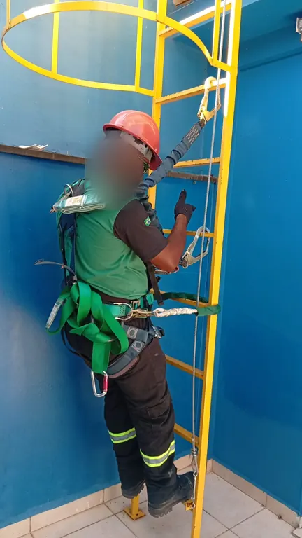 Aluno com cinto paraquedista subindo escada tipo marinheiro na prática de trabalho em altura