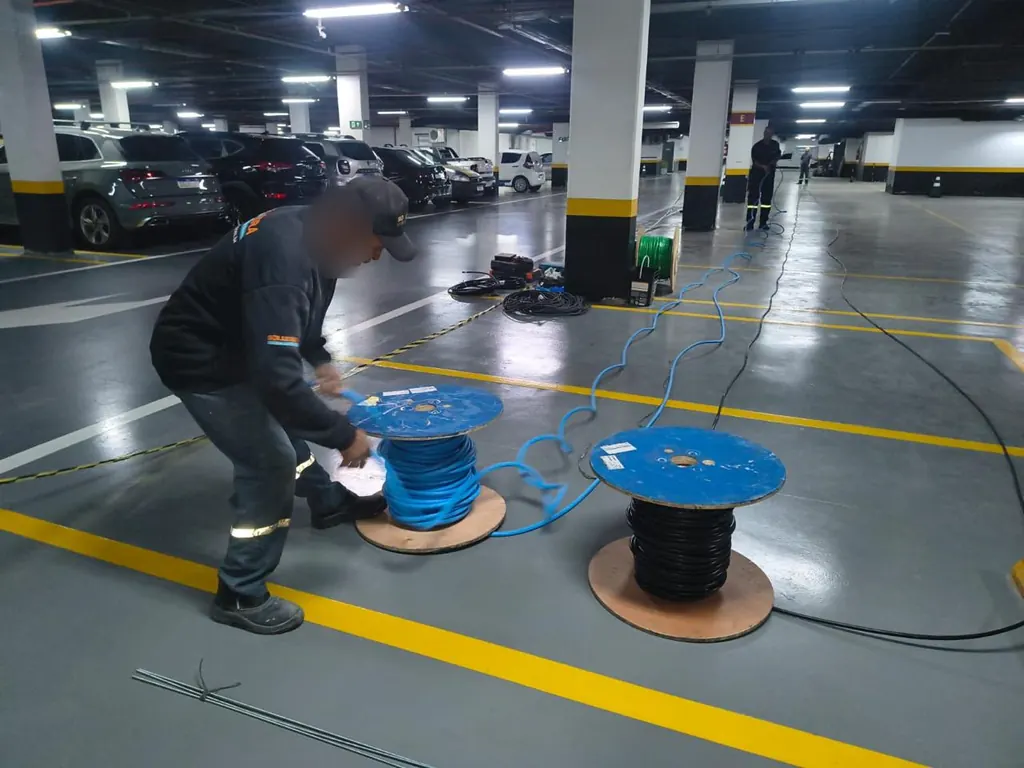 Eletricista desenrolando bobina de cabo em garagem